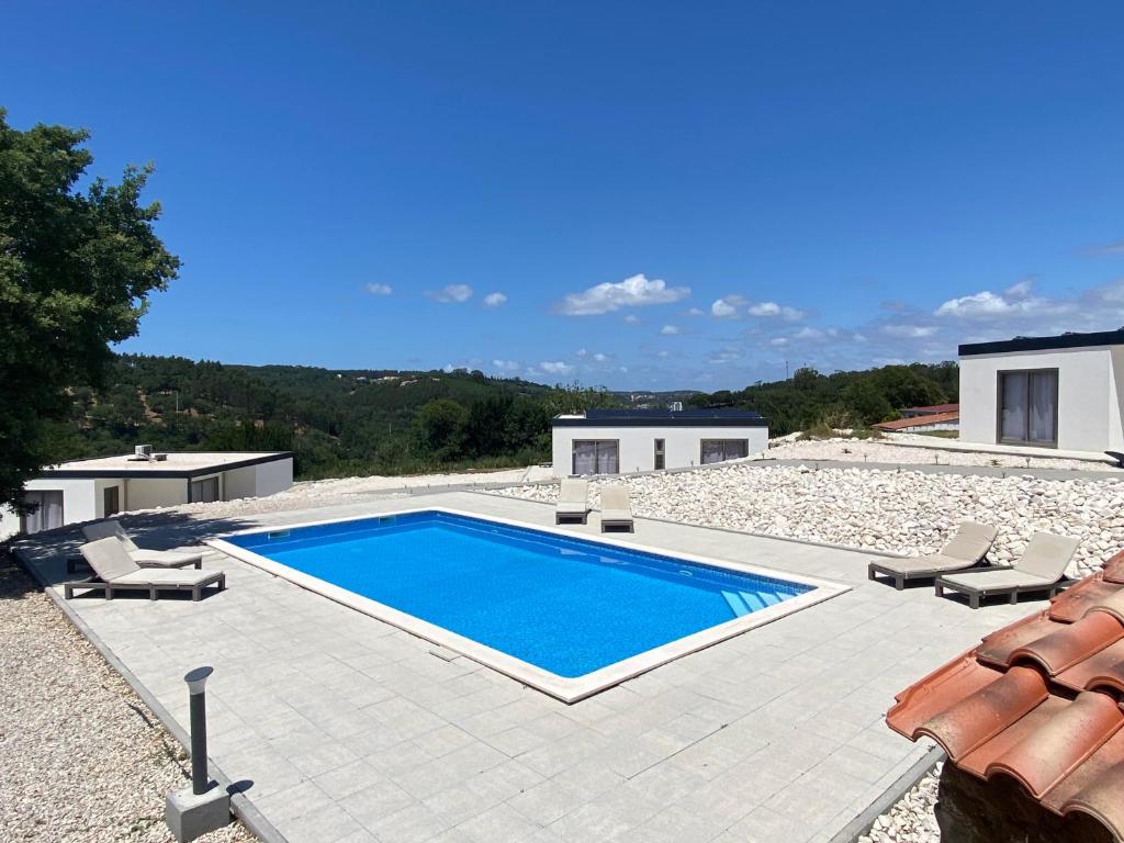 a swimming pool with chairs and a house at Quinta Estrela d'Alva in Alcobaça