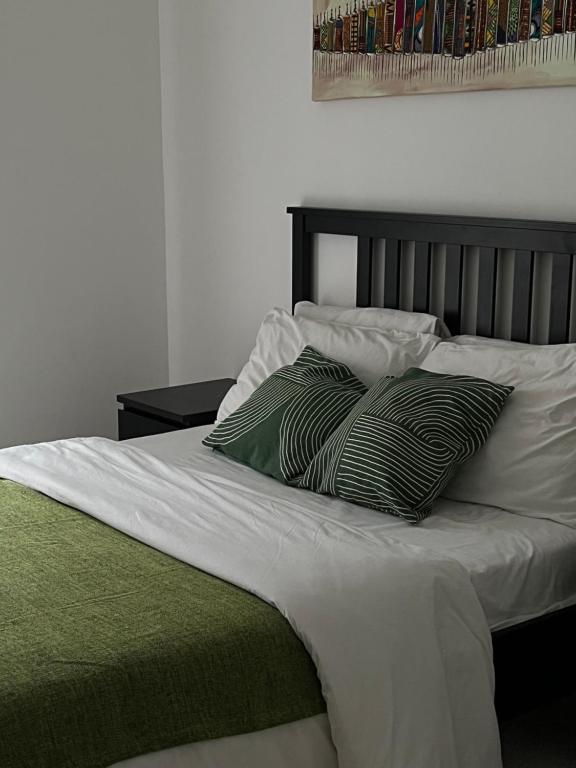 a bed with two green and white pillows on it at ‪Luxury One Bed Apt w/Balcony in Cantonment in Accra