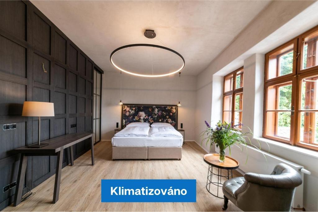 a bedroom with a bed and a desk and windows at Hotel Clemar in Znojmo