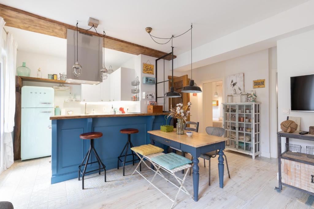 una cocina con una isla azul y una mesa en Astoria - baskeyrentals en San Sebastián