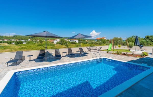a large swimming pool with chairs and umbrellas at Villa Strkalj Bibinje in Bibinje
