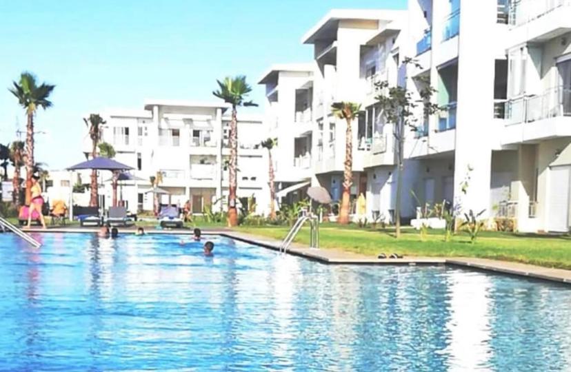 uma piscina em frente a alguns edifícios de apartamentos em Casabay appartement pied dans l'eau 87 m2 em Sidi Rahal