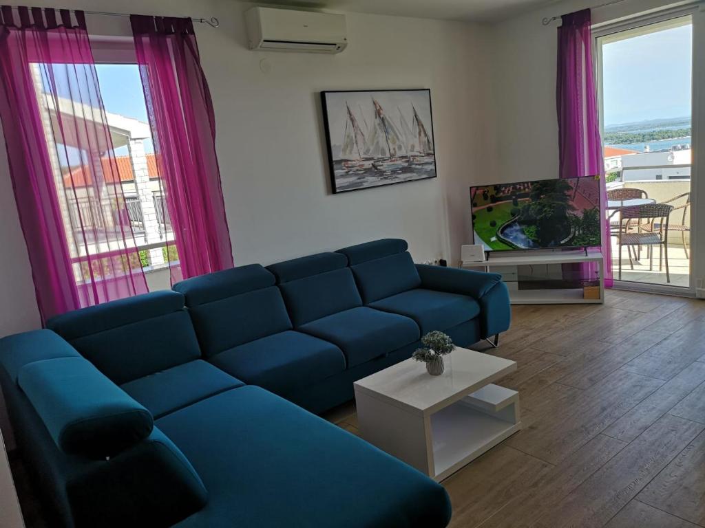 a living room with a blue couch and a tv at VillaTea in Murter