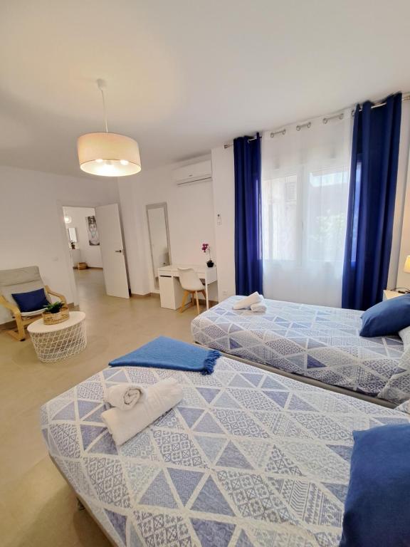 two beds in a large room with blue curtains at Villa Las Tres J in Málaga