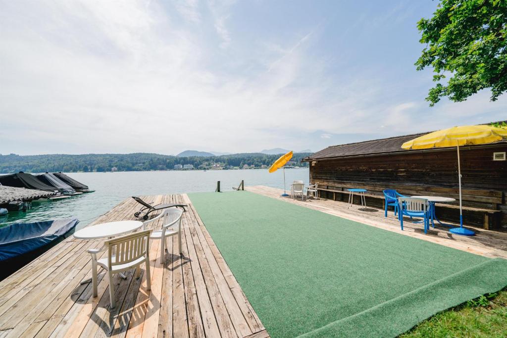 a dock with chairs and a table and an umbrella at Gästehaus Frank in Velden am Wörthersee