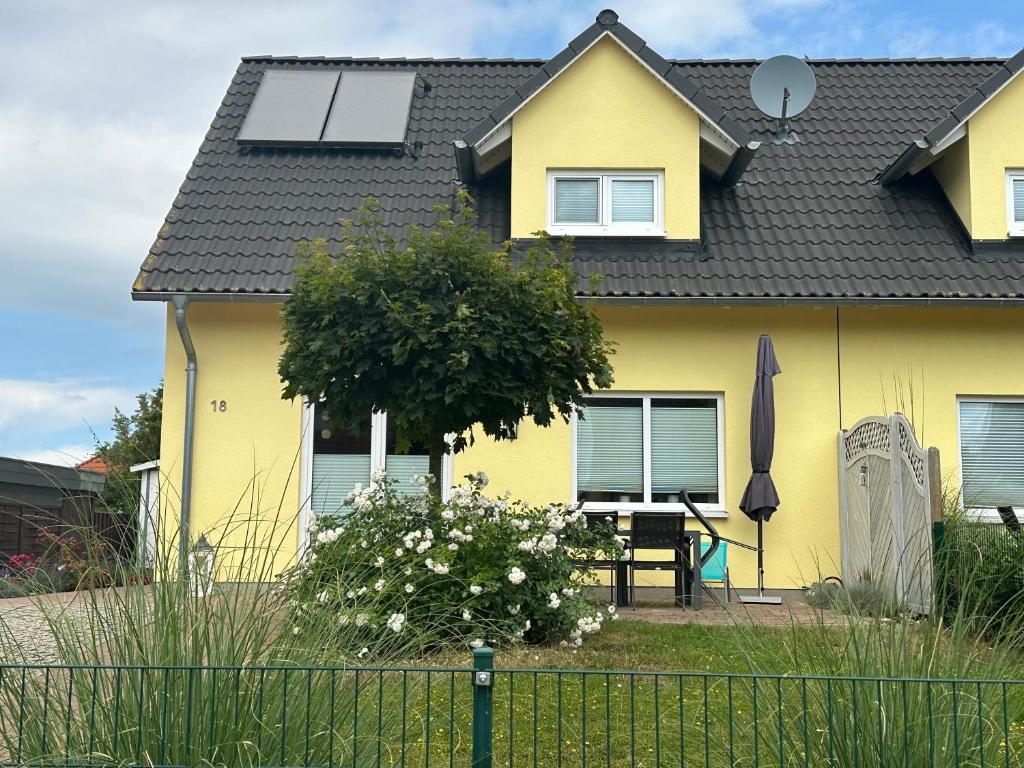 une maison jaune avec des panneaux solaires sur le toit dans l'établissement Ostseeauszeit Blengow, à Rerik