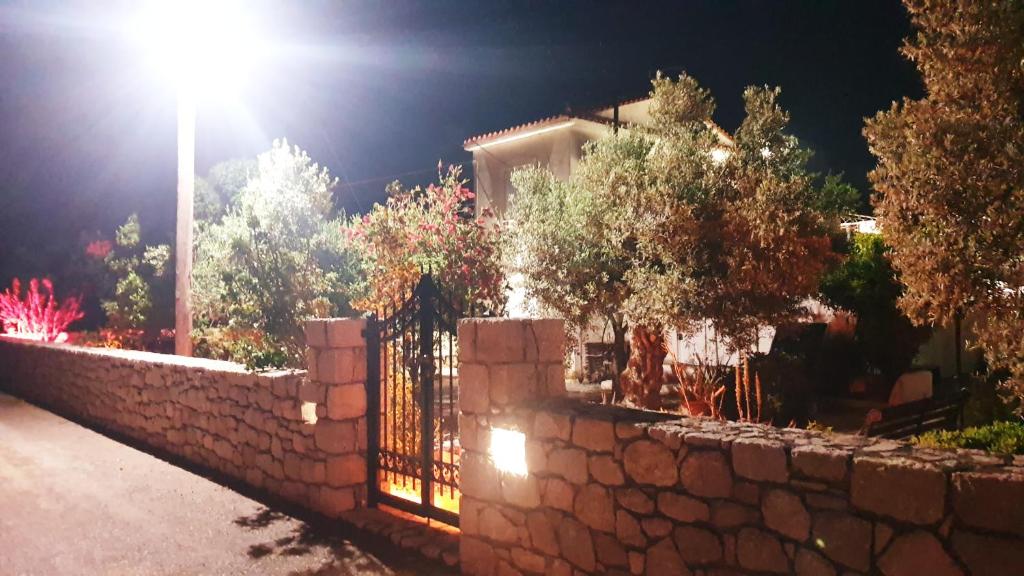 una cerca de piedra frente a una casa por la noche en Villa Stamatis, en Áyioi Apóstoloi