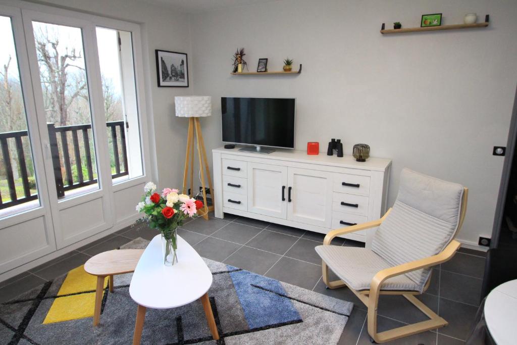ein Wohnzimmer mit einem TV, einem Tisch und Stühlen in der Unterkunft Le 59 Vue Mer in Villers-sur-Mer