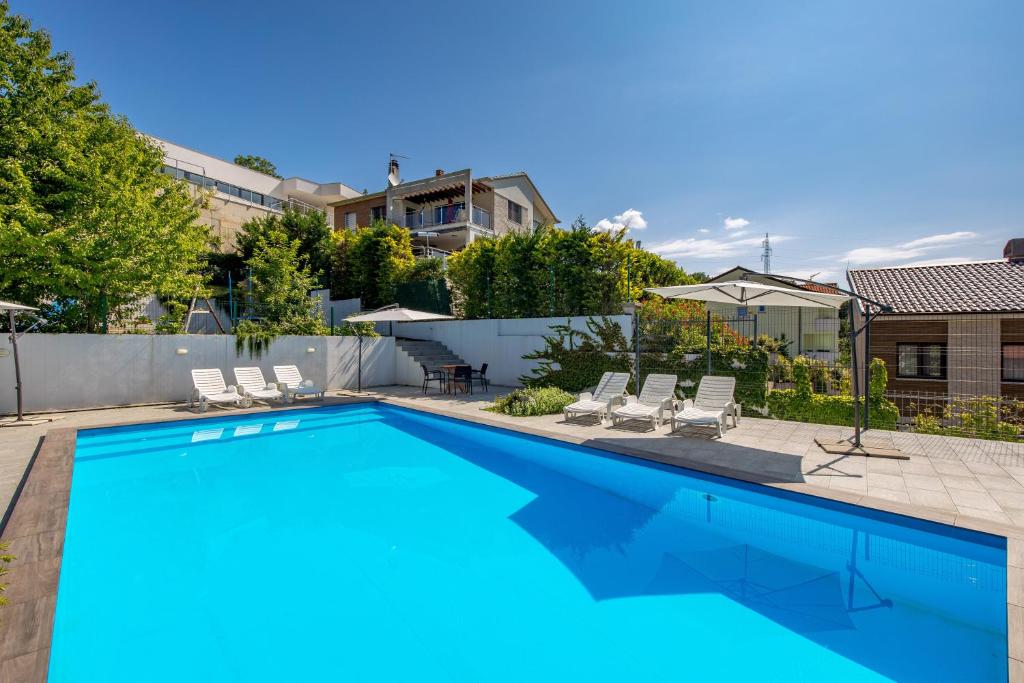 a swimming pool with chairs and a house at Villa Oleander Apartman Aria in Poljane