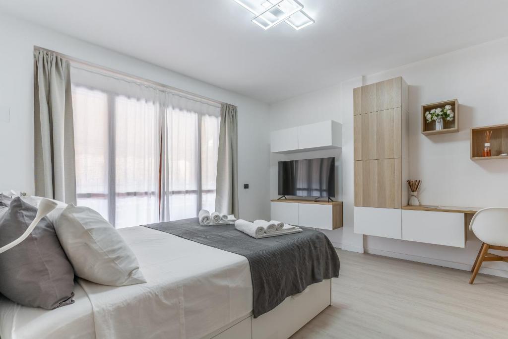 a white bedroom with a bed and a television at Santa Giulia Suite in Milan