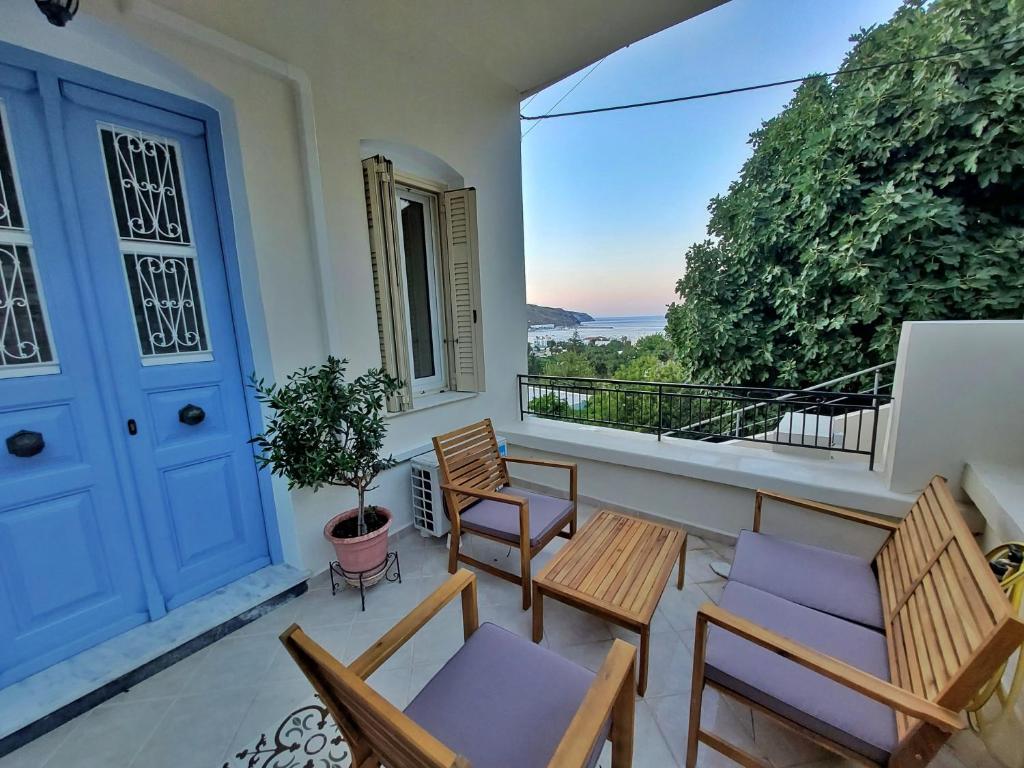 a balcony with chairs and tables and a blue door at Theros Home Andros in Andros