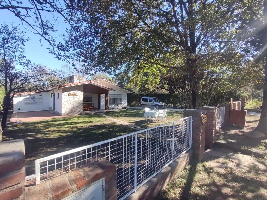 ein Haus mit einem Zaun vor einem Hof in der Unterkunft La Casa de Belén in Villa General Belgrano