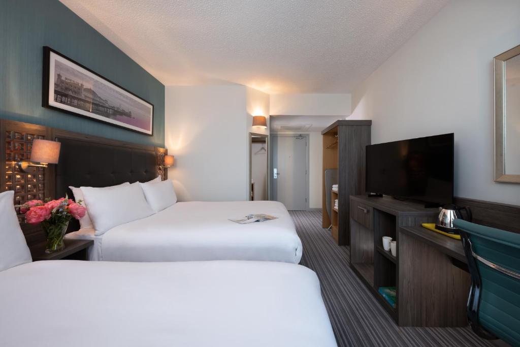 a hotel room with two beds and a flat screen tv at Leonardo Hotel Brighton in Brighton & Hove