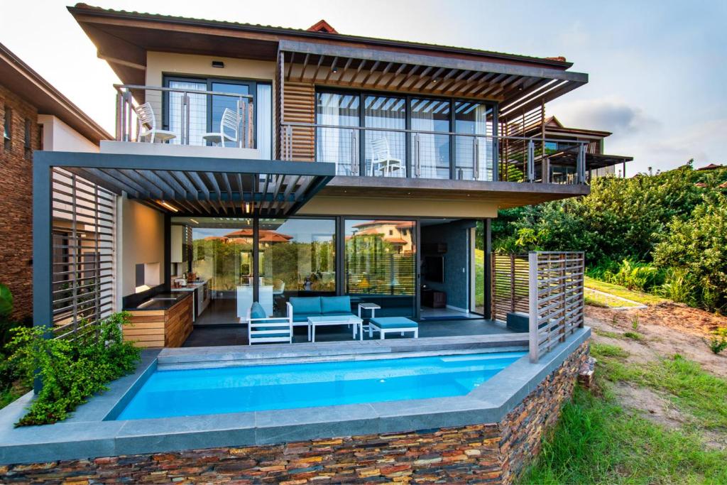 a home with a swimming pool in front of a house at Oceans Edge 5, Zimbali Estate in Ballito