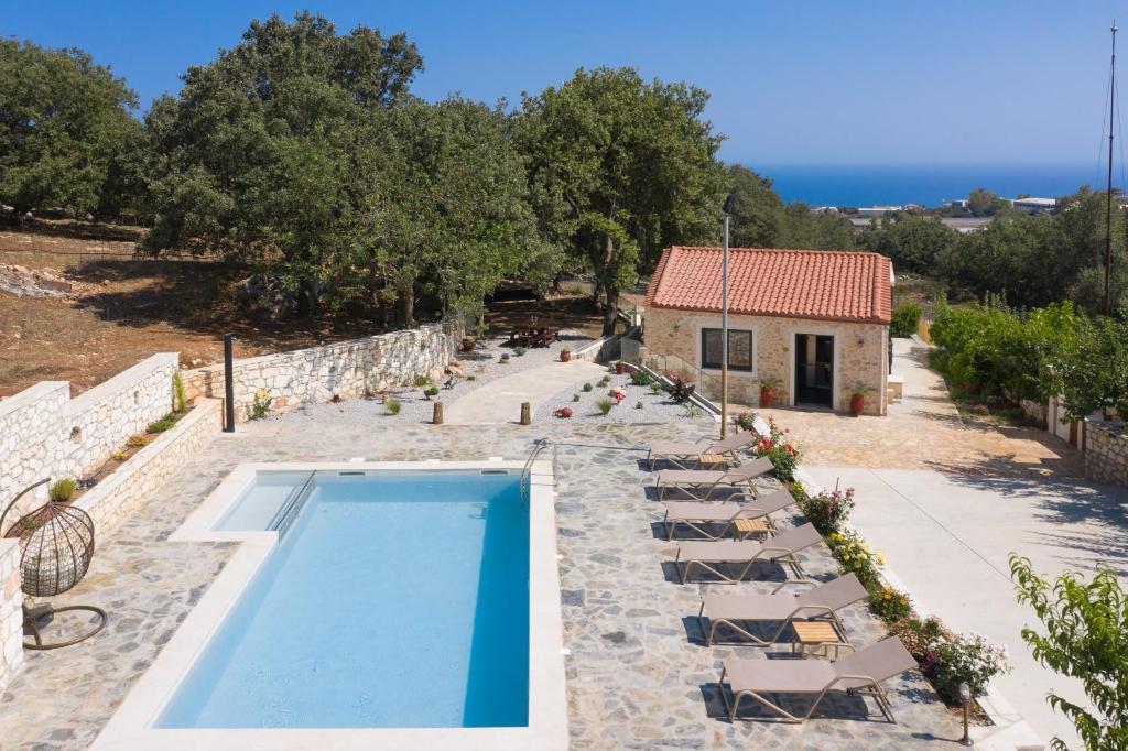 a swimming pool with chairs and a building at Mouria Country House in Gállos