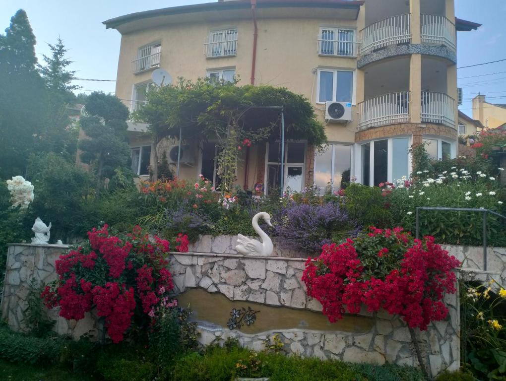 uma casa com flores e um cisne à sua frente em Guest house Bankya em Bankya