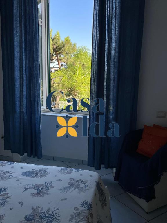a bedroom with a window with blue curtains and a bed at Amalfi Coast Casa Ida in Vietri sul Mare