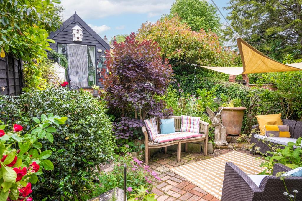 a garden with a patio with a chair and flowers at Alec Hill's Bakehouse in Wangford
