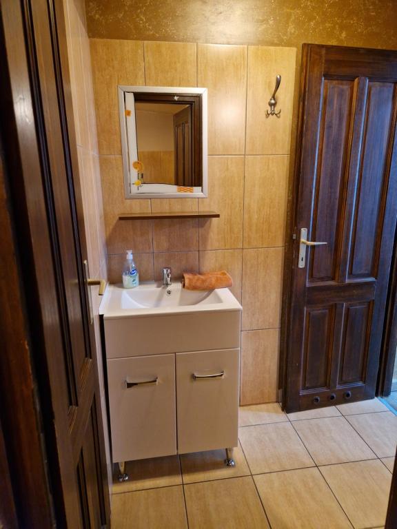 baño con lavabo, espejo y puerta en Splendor apartman, en Debrecen