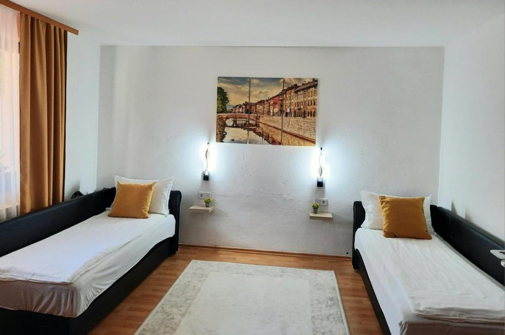 a room with two beds and a painting on the wall at Apartman Kovaci in Sarajevo