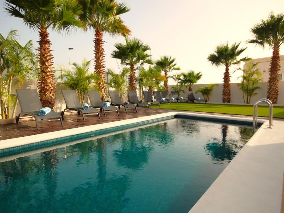 a swimming pool with chairs and palm trees at Villa de lujo con piscina privada en Costa Adeje in Adeje