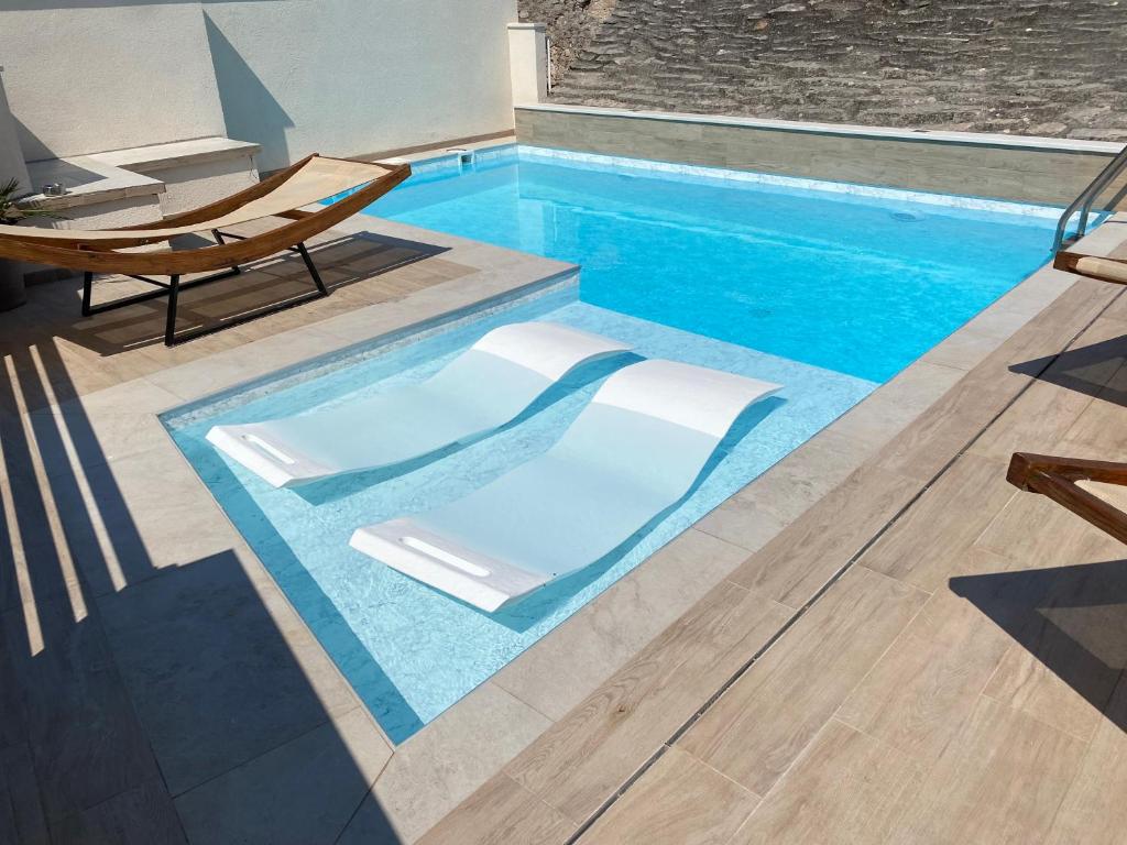 una piscina con un banco y una silla al lado en Apartments Villa De Blue, en Bol