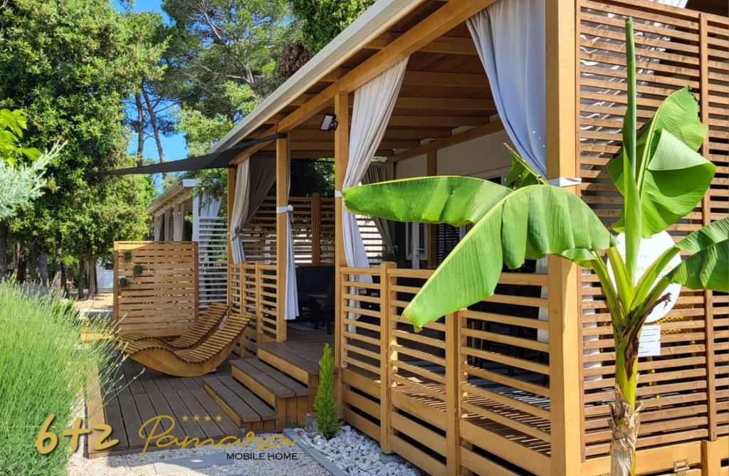 a house with a wooden deck with a chair at PAMARA Mobile Home in Biograd na Moru