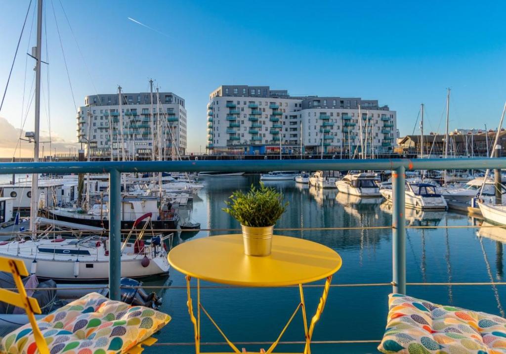a yellow table and chairs on a balcony with boats at On the Water 4 with Free Parking By My Getaways in Brighton & Hove