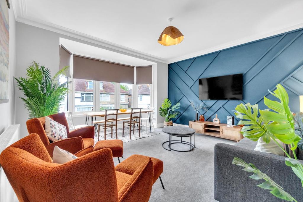 a living room with orange chairs and a blue wall at Poets Apartment with Free Parking By My Getaways in Worthing