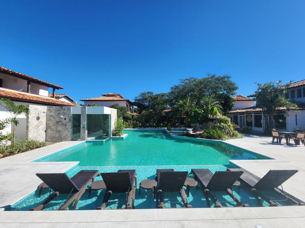 a swimming pool with chaise lounge chairs and a resort at Pousada dos Tangarás in Búzios