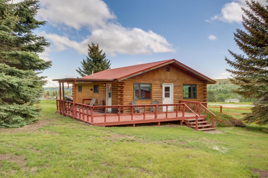een blokhut met een groot terras in een veld bij Red Lodge Vacation Rental with Mountain Views! in Red Lodge