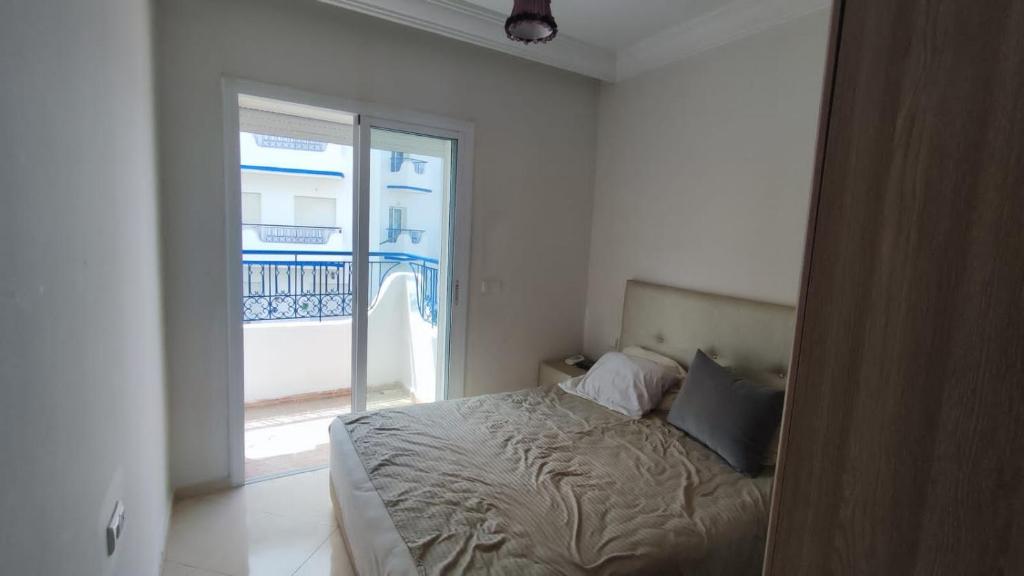 a bedroom with a bed with a view of a balcony at Jolie appartement avec piscine à Ryad Sofia Martil,Tetouan in Martil