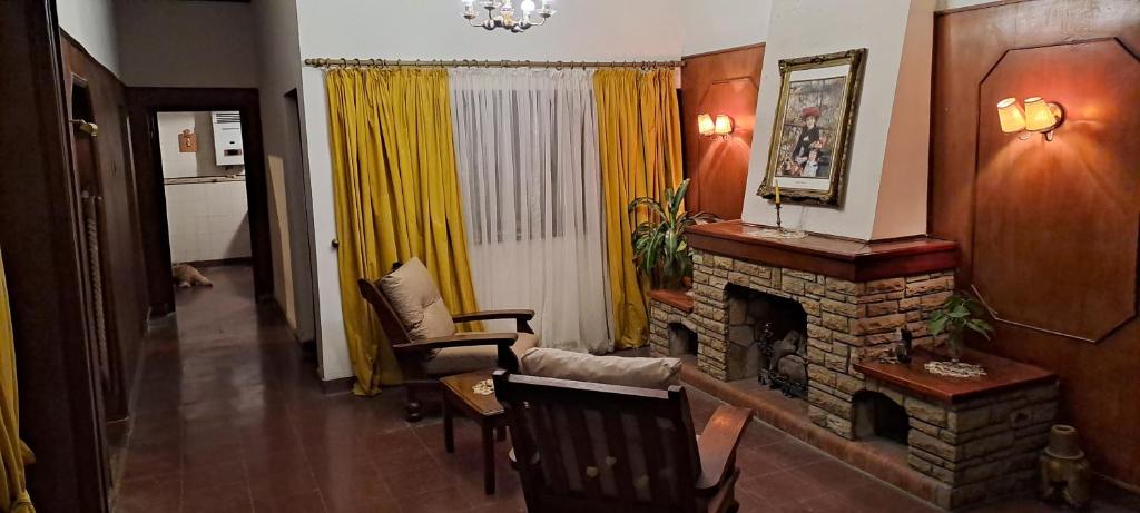 uma sala de estar com lareira e cortinas amarelas em Casa Linda em Salta