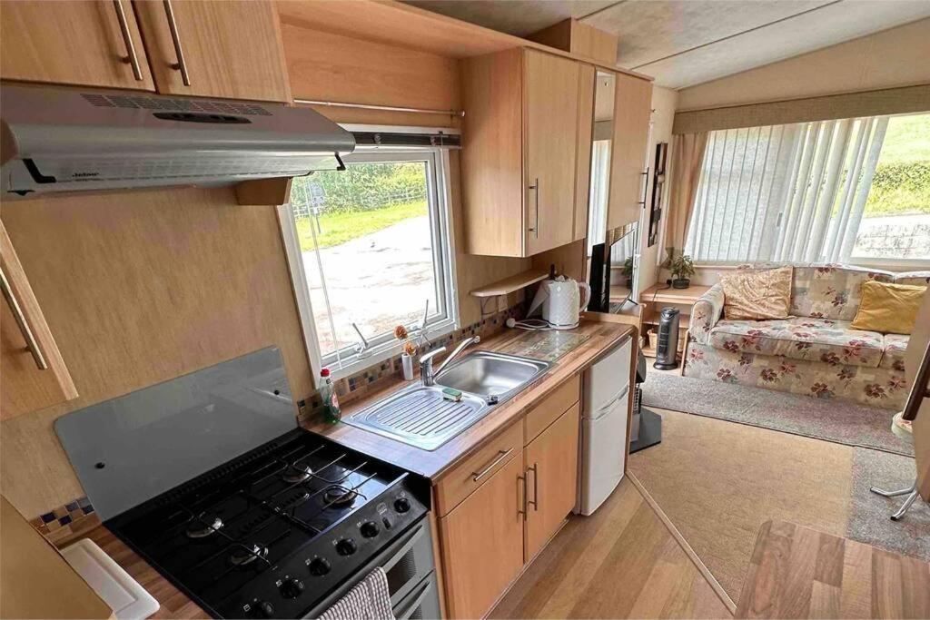 una caravana con cocina con fogones y fregadero. en 4-Bedroom Cosalt Parkhome in Uddingston, Glasgow en Uddingston