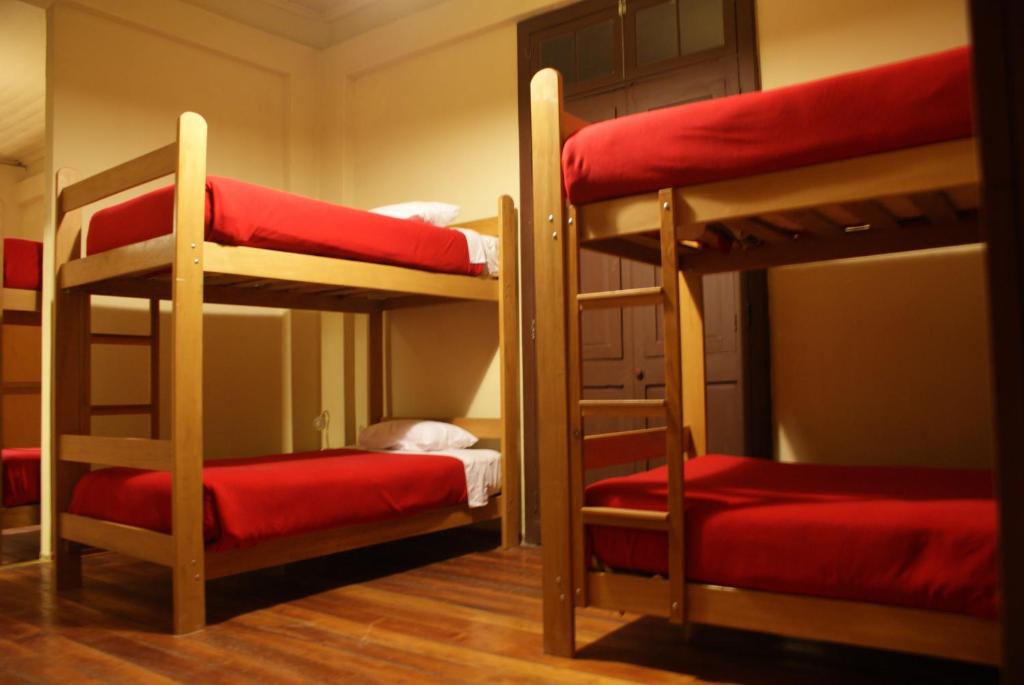 a room with two bunk beds with red sheets at Flying Dog Hostel Arequipa in Arequipa