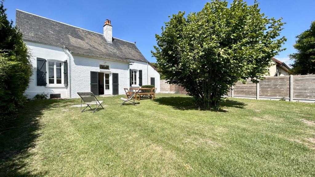 une maison blanche avec des chaises et un arbre dans la cour dans l'établissement Nolette en baie maison de campagne, à Noyelles-sur-Mer