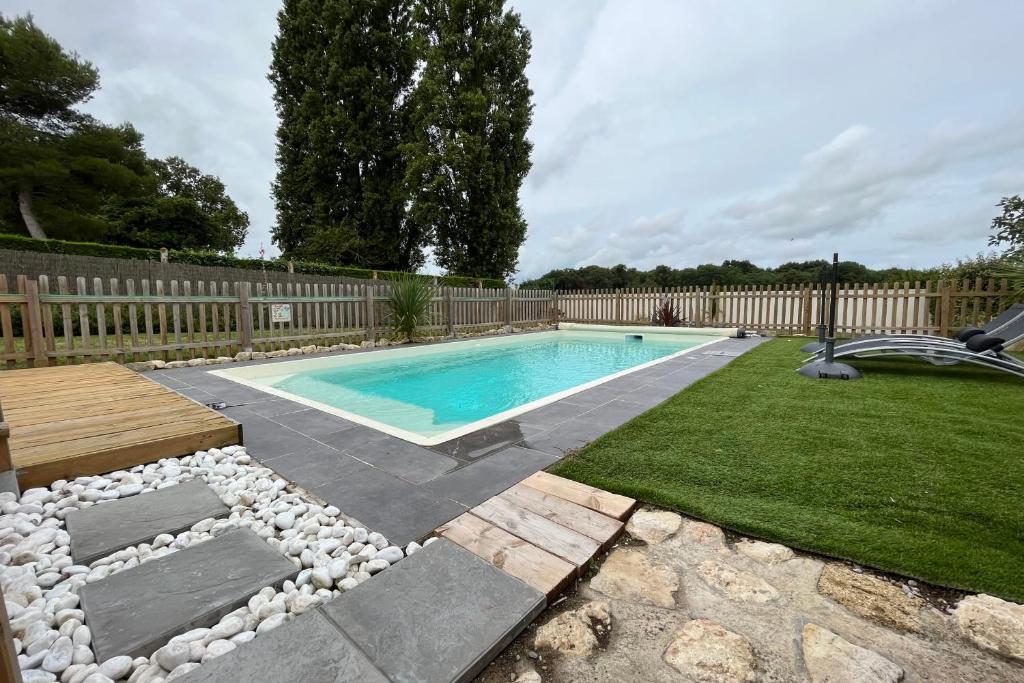 a swimming pool in a backyard with a wooden fence at Elma Stay Location LEscale in Saint-Just