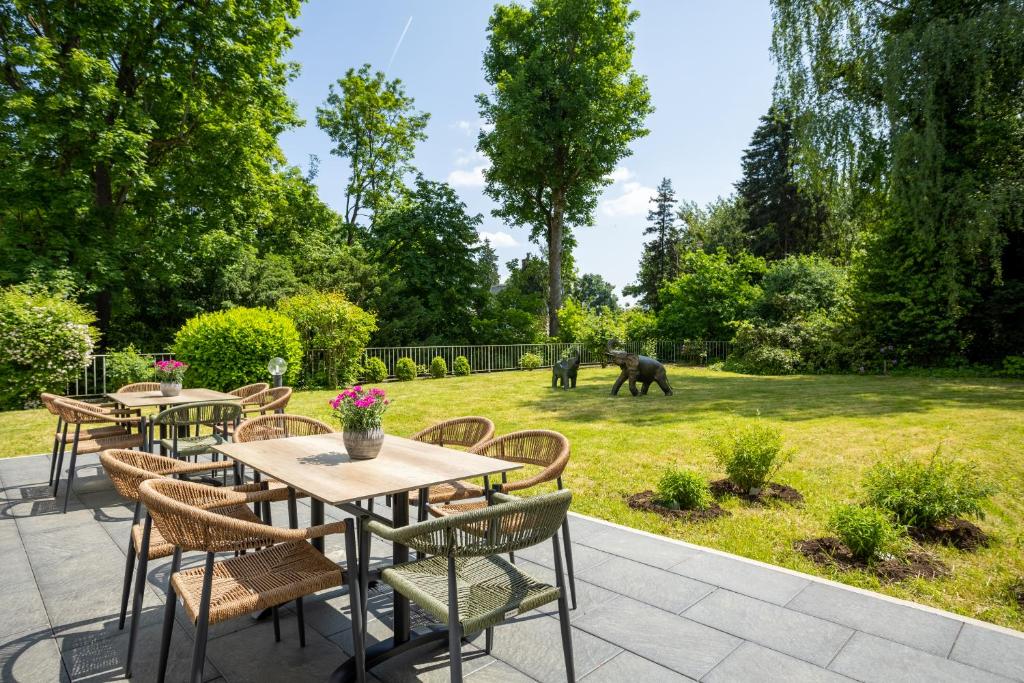 eine Terrasse mit Tischen und Stühlen im Garten in der Unterkunft Concorde Hotel Viktoria in Kronberg im Taunus