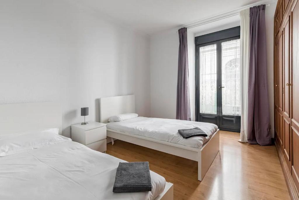 a white bedroom with two beds and a window at AVE Apartamentos Madrid Centro Atocha in Madrid