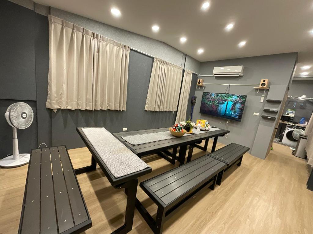 uma sala de jantar com uma mesa e bancos e uma televisão em 好日子914包棟6房Ktv民宿 em Kaohsiung