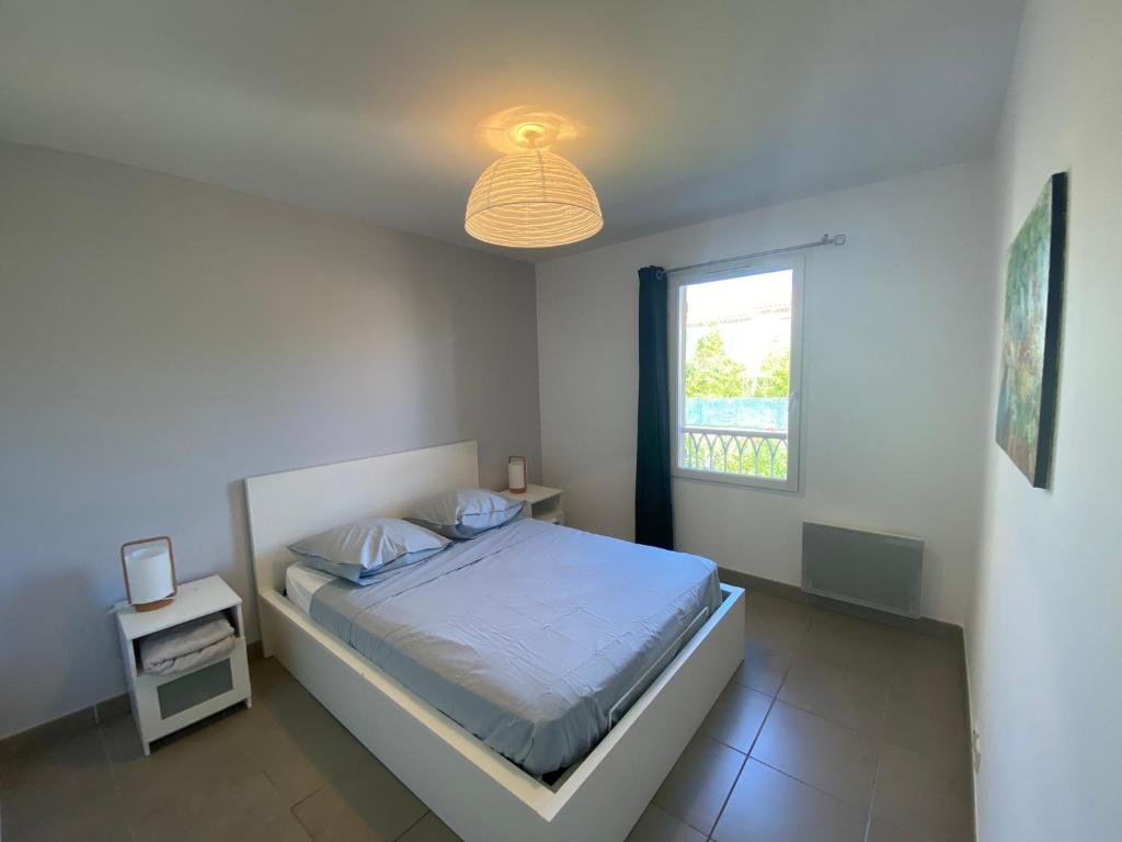 ein weißes Schlafzimmer mit einem Bett und einem Fenster in der Unterkunft Maison avec piscine, climatisée, proche plage in Roquebrune-sur-Argens