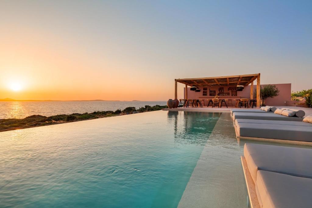 a swimming pool with a sunset in the background at Akre Hotel in Naxos Chora