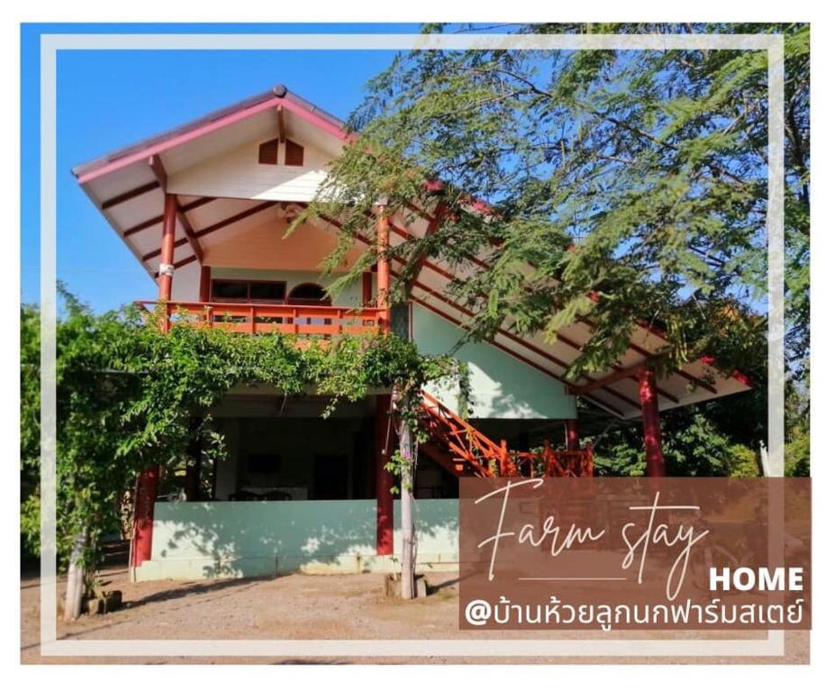 una casa con un cartel delante de ella en บ้านห้วยลูกนกฟาร์มสเตย์ Banhuailuknok Farmstay en Ratchaburi