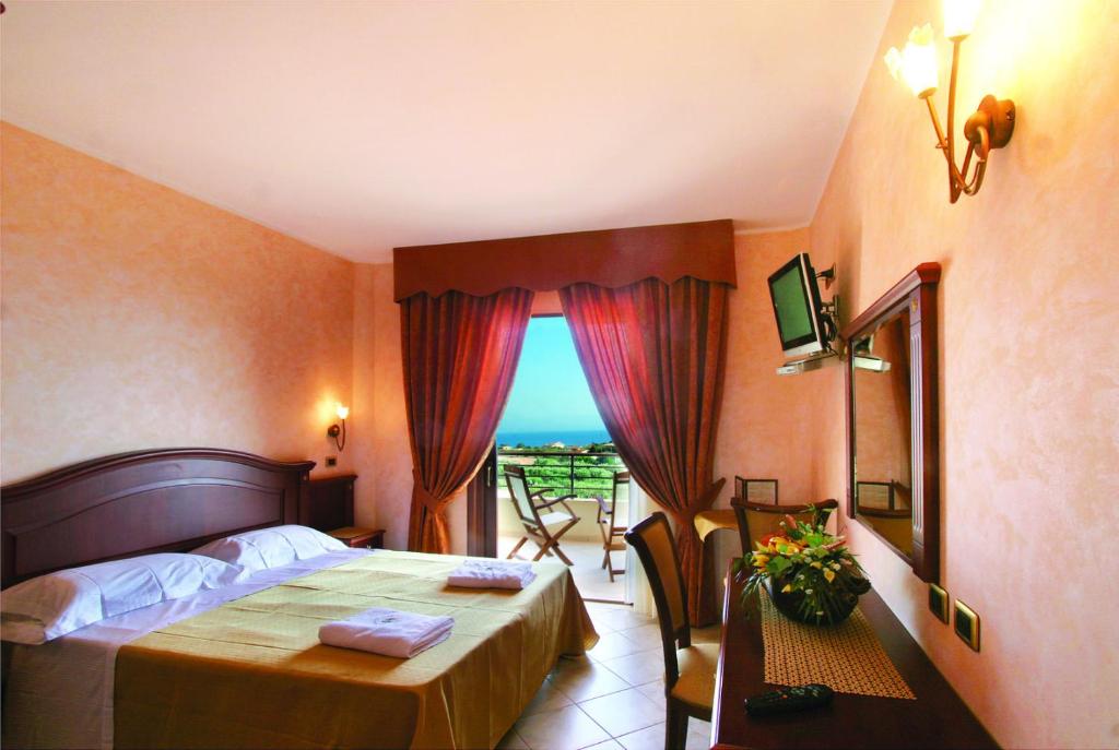 a bedroom with a bed and a table and a window at Hotel Santa Chiara in Capo Vaticano