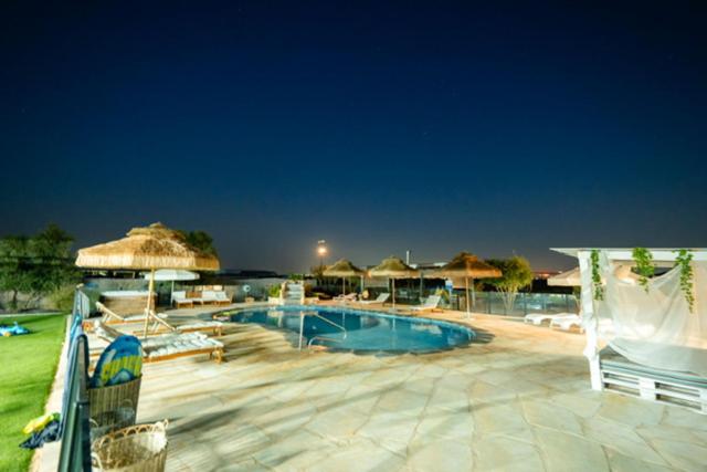 a swimming pool with chairs and umbrellas at a resort at Atnachta BaGilboa in Addirim