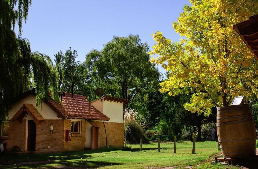 a small brick house in a yard with trees at Cabaña en Alta Montaña - Complejo Cabañas del Pastizal - USPALLATA, MENDOZA in Uspallata