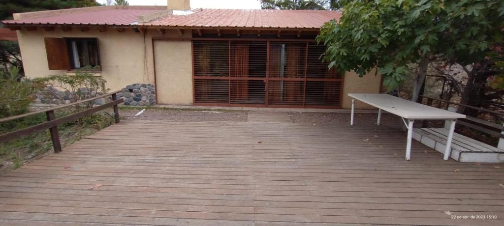 una terraza de madera con un banco frente a una casa en Chalet Villalís en Potrerillos