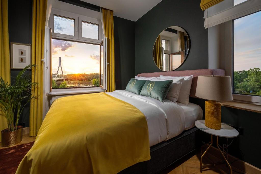 1 dormitorio con 1 cama con manta amarilla y ventana en Sava Boutique Hotel, en Varsovia