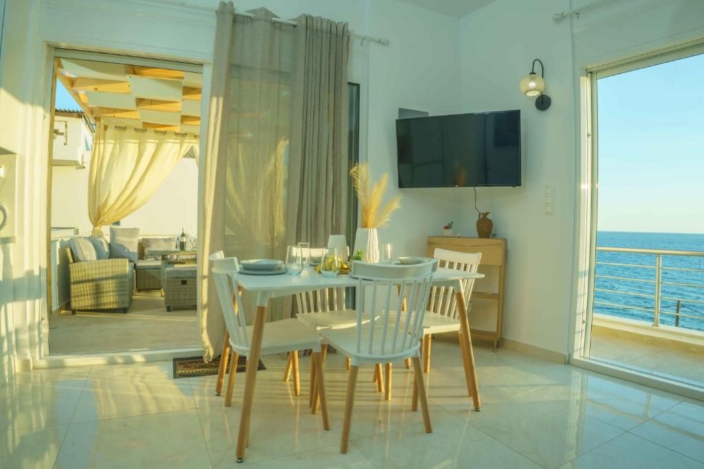 a dining room with a table and chairs with a view of the ocean at Cocoscape Suite, seaside & 270° open view in Kalamaki Heraklion