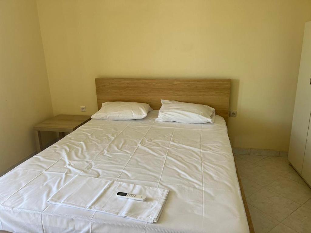 a bed with white sheets and a wooden head board at Sunset Apartment in Vonitsa